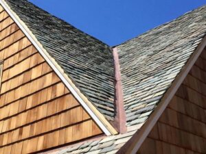 A close-up view of a completed slate shingle roof and natural wood siding on a home by Prescott Roofing and Masonry in Carnegie, PA.