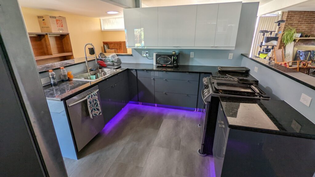 A sleek, modern kitchen with dark cabinets and purple under-cabinet lighting, a project by The Foundation Guys in Lakewood, CO