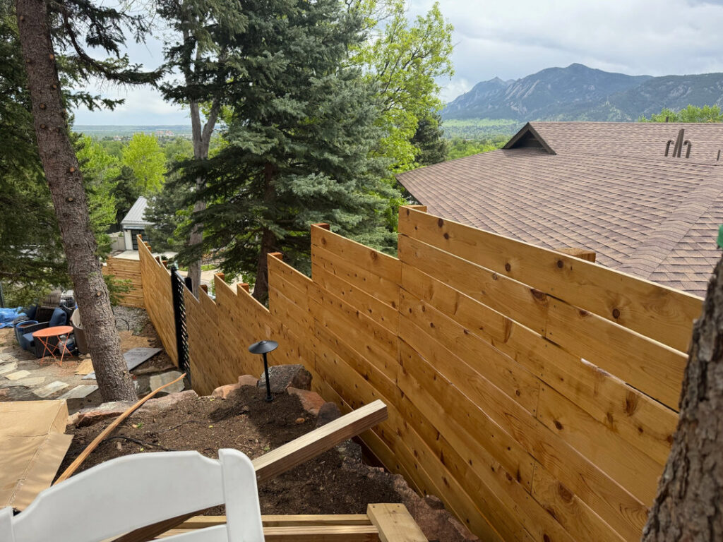 A horizontal wood fence installed on a sloped terrain by GreenView Solutions in Denver, CO.
