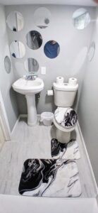 A renovated small bathroom or powder room with a pedestal sink, toilet, and decorative mirrors by Prime Construction And Flooring in Lorain, OH.