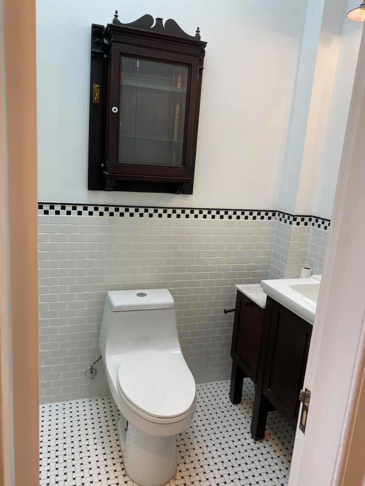 Small bathroom remodel with new toilet, vanity, and intricate tile work on walls and floor by MTI Carpentry in Jersey City, NJ.