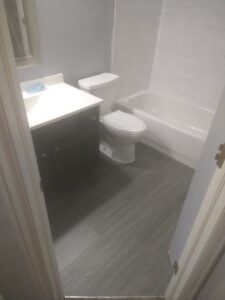 A completed small bathroom renovation featuring a new vanity, toilet, tub, and flooring by Mr. Affordable LLC in Denver, CO.