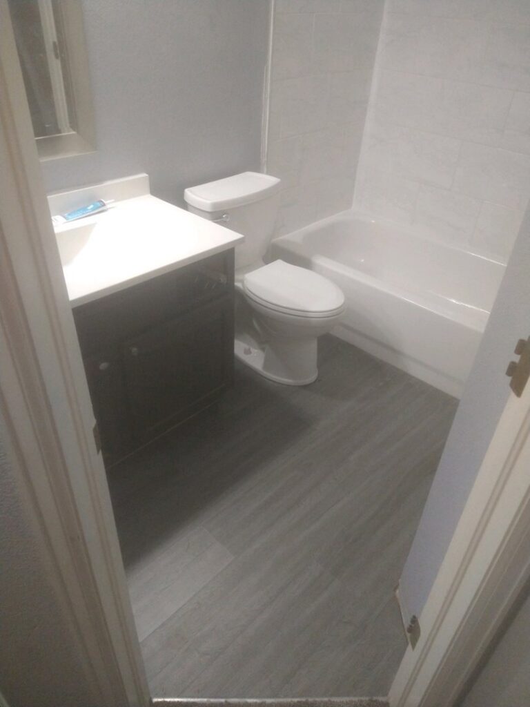 A completed small bathroom renovation featuring a new vanity, toilet, tub, and flooring by Mr. Affordable LLC in Denver, CO.