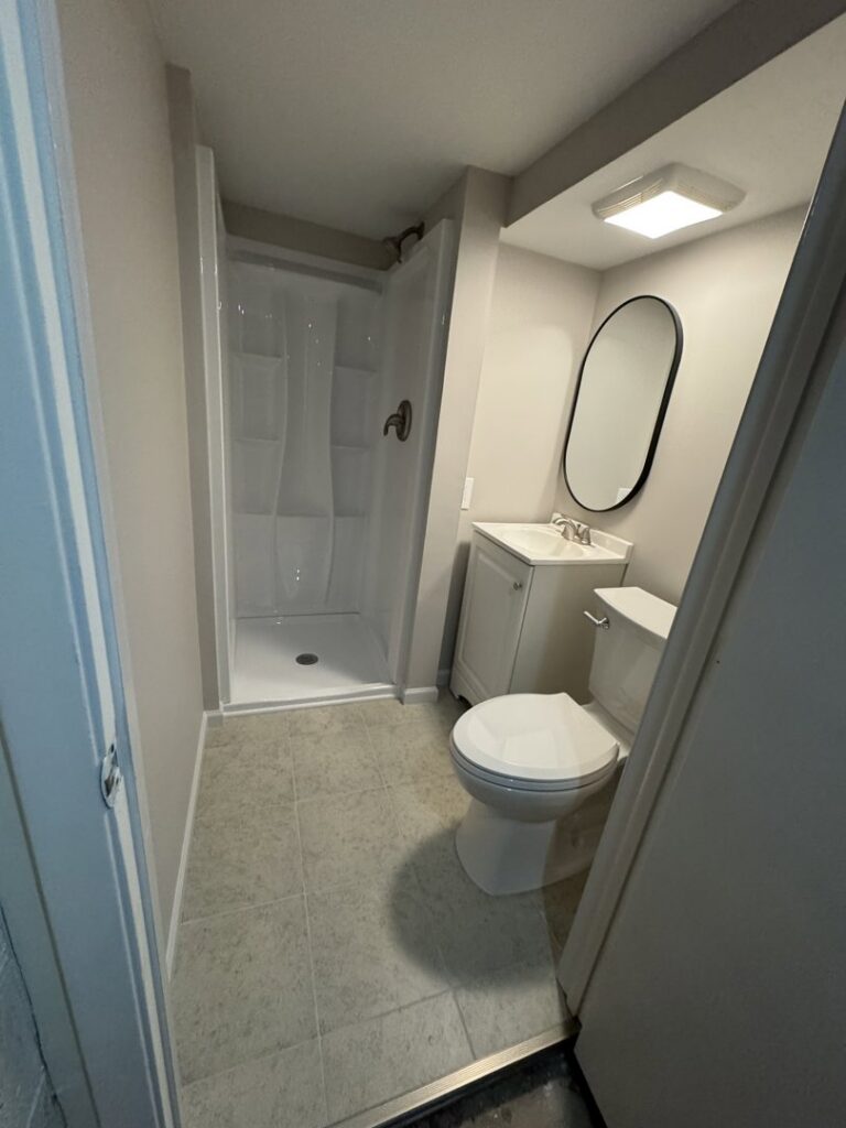 A small, newly renovated bathroom featuring a stand-up shower, modern vanity, and tiled flooring by Prime Construction And Flooring in Lorain, OH.