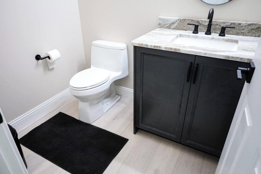 A compact bathroom featuring a new dark vanity and toilet installed by Kore Construction LLC in Cincinnati, OH.
