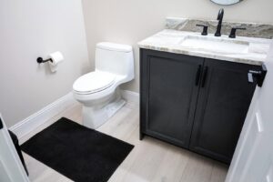 A compact bathroom featuring a new dark vanity and toilet installed by Kore Construction LLC in Cincinnati, OH.