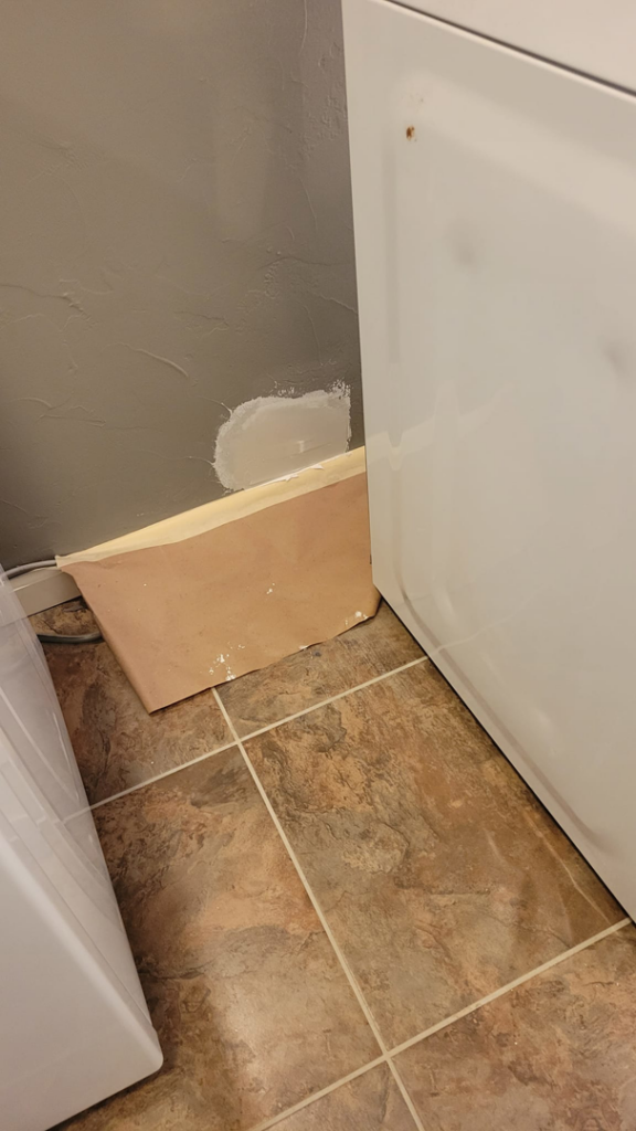 Small drywall patch repair near a washing machine in a laundry room by M&M Drywall and Construction in Enid, OK