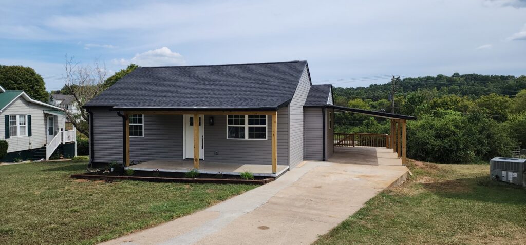 A newly renovated small house with gray siding, new roof, and covered porch by Rapid Repairs and Renovations in Knoxville, TN.