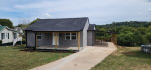 A newly renovated small house with gray siding, new roof, and covered porch by Rapid Repairs and Renovations in Knoxville, TN.