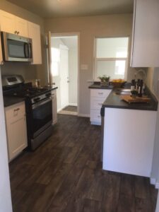 A newly remodeled small kitchen with white cabinets and dark countertops by J & D Home Innovations in West Jordan, UT