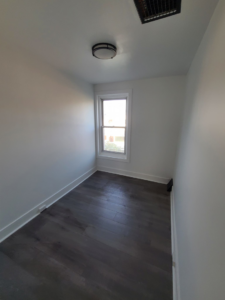 A newly renovated small room featuring dark wood-look flooring and white walls by Modern Image Construction LLC in El Paso, TX