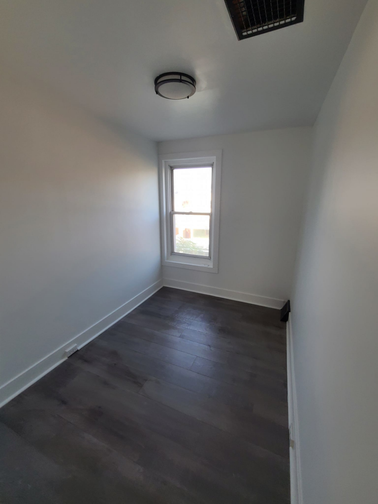 A newly renovated small room featuring dark wood-look flooring and white walls by Modern Image Construction LLC in El Paso, TX