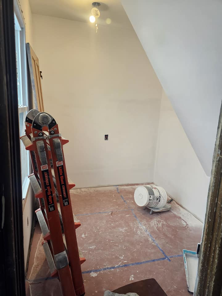 A small room under renovation with ladders and paint supplies, showcasing work by Done Well Home Improvement LLC in Buffalo, NY.