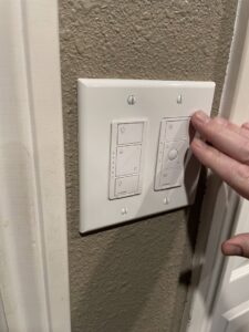 A hand operating a newly installed smart light switch and dimmer by Absolute Integrity Handyman Services Inc in Fresno, CA.