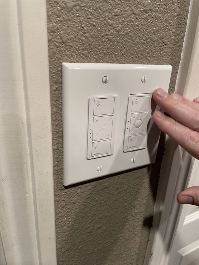 A hand operating a newly installed smart light switch and dimmer by Absolute Integrity Handyman Services Inc in Fresno, CA.