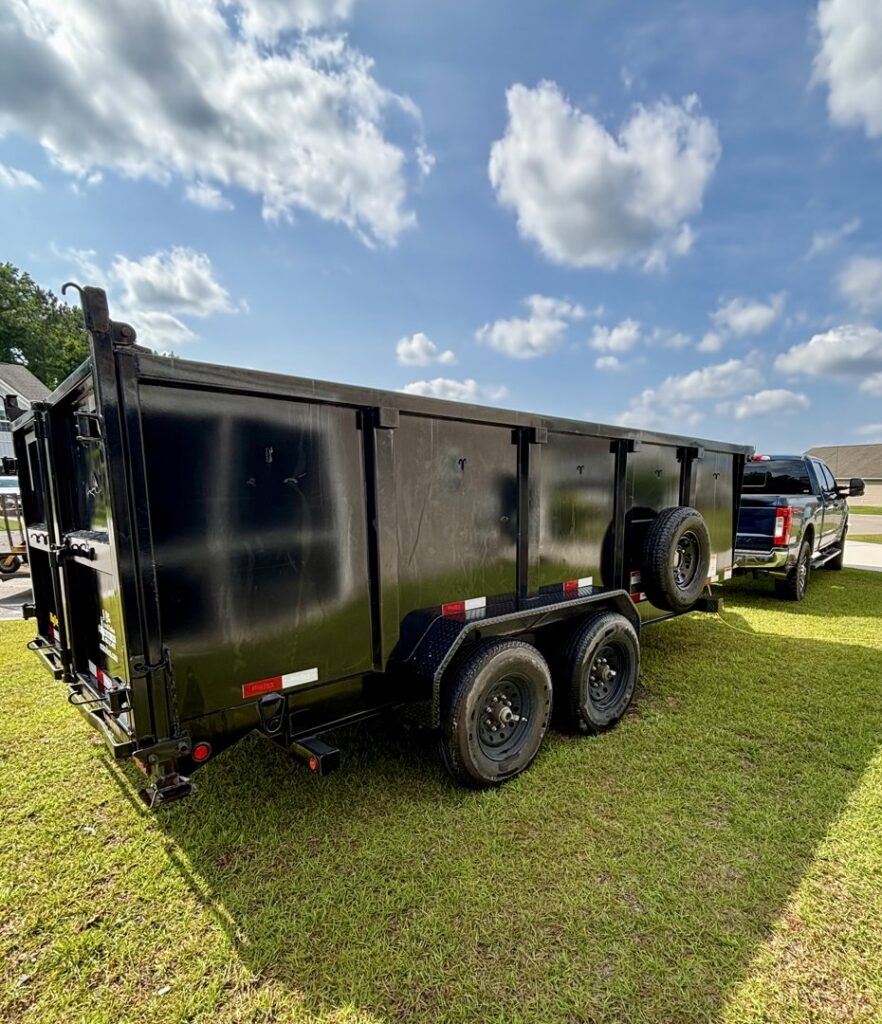 An empty SmartDumps black dump trailer attached to a pickup truck, ready for junk removal in Wilmington, NC.