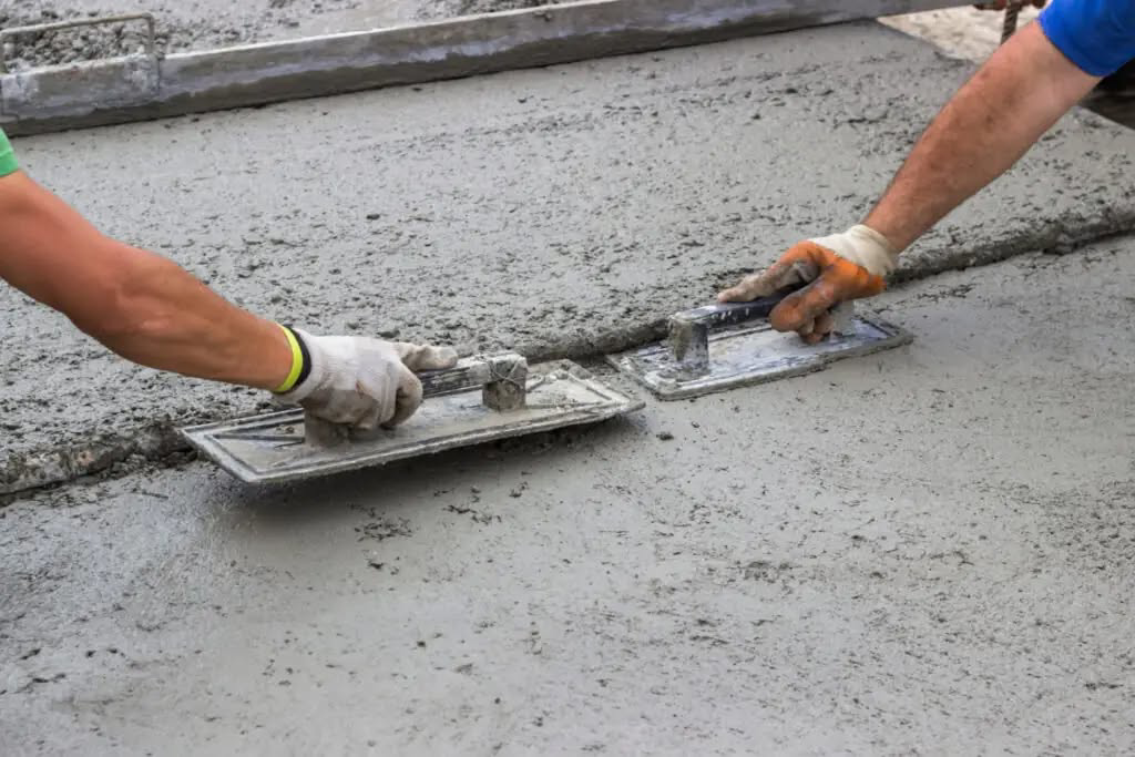 Close-up of hands smoothing a fresh concrete surface with floats by Cervantes Concrete Llc in Caledonia, WI.
