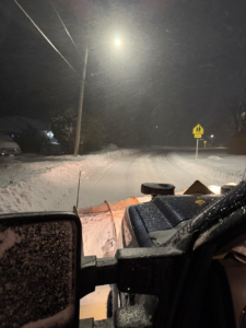 A snow plow truck clearing a street at night, provided by A Bit Of Everything LLC in Cranston, RI.