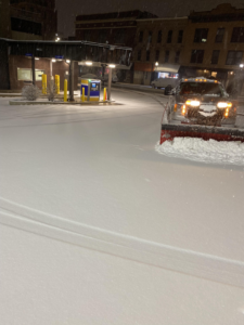 A snow removal truck clearing a parking lot at night, a property service by PG Contractors Property Services Inc. in Naperville, IL.
