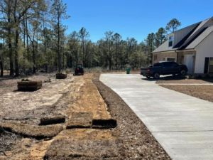 Sod installation in progress with rolls of sod and a tractor by Stokes Contracting LLC in Mobile, AL