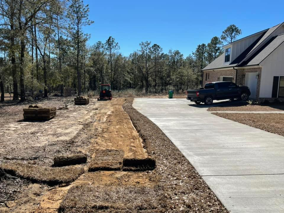 Sod installation in progress with rolls of sod and a tractor by Stokes Contracting LLC in Mobile, AL