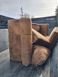 A large brown sofa loaded into a dump trailer for junk removal by T-Rex Service LLC in Cheyenne, WY.