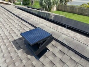 A newly installed solar attic fan and solar panels on a roof by Koala Insulation of Charlotte, NC