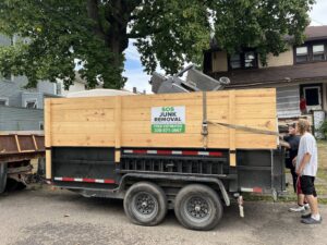 A Sos Junk Removal trailer loaded with various debris and junk, with two workers on site in Akron, OH.