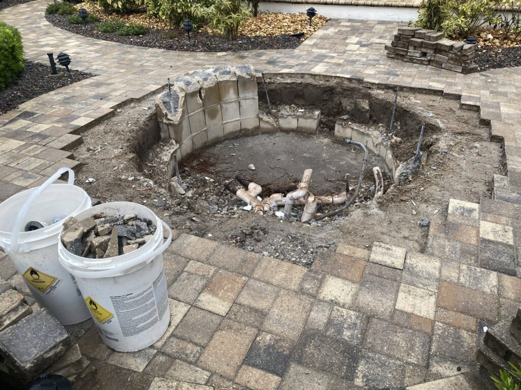Spa demolition and excavation in progress, showing exposed pipes and debris, handled by JJB Pools & Spas in Tampa, FL.