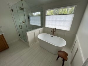 A spacious bathroom remodel with a glass-enclosed shower and a freestanding tub by Benjamin Design - Build in Fishers, IN.