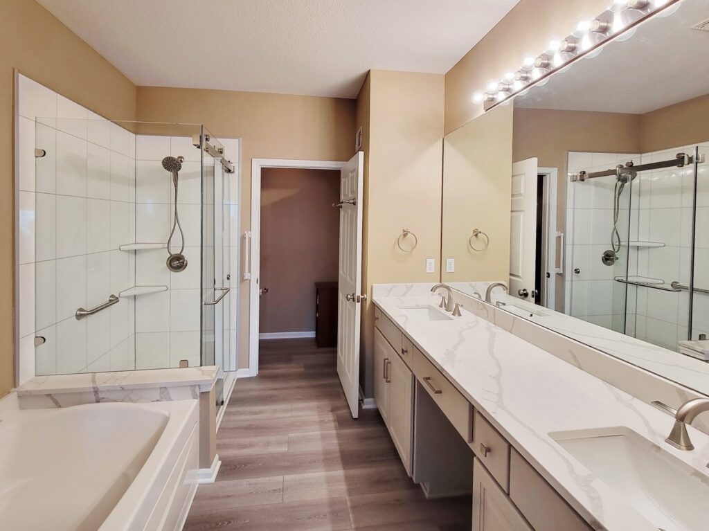 A spacious bathroom remodel featuring a double vanity, walk-in shower, and tub by Thrive Homes, LLC in Olathe, KS.