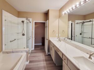 A spacious bathroom remodel featuring a double vanity, walk-in shower, and tub by Thrive Homes, LLC in Olathe, KS.