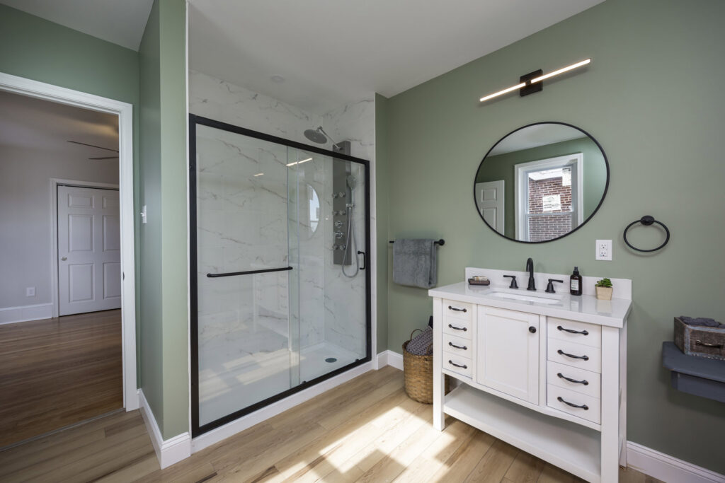 A spacious bathroom remodel featuring a large walk-in shower with glass doors and a modern vanity by Tile Jawn in Philadelphia, PA.
