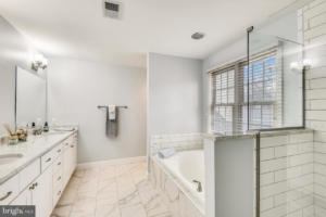 A spacious bathroom renovation with white tiles, a double vanity, bathtub, and walk-in shower by Prestige Services in Annapolis, MD.