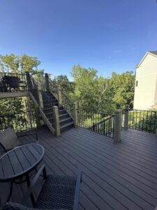 A spacious deck with stairs leading down to the yard, complete with outdoor seating by Deckscape KC in Kansas City, MO.