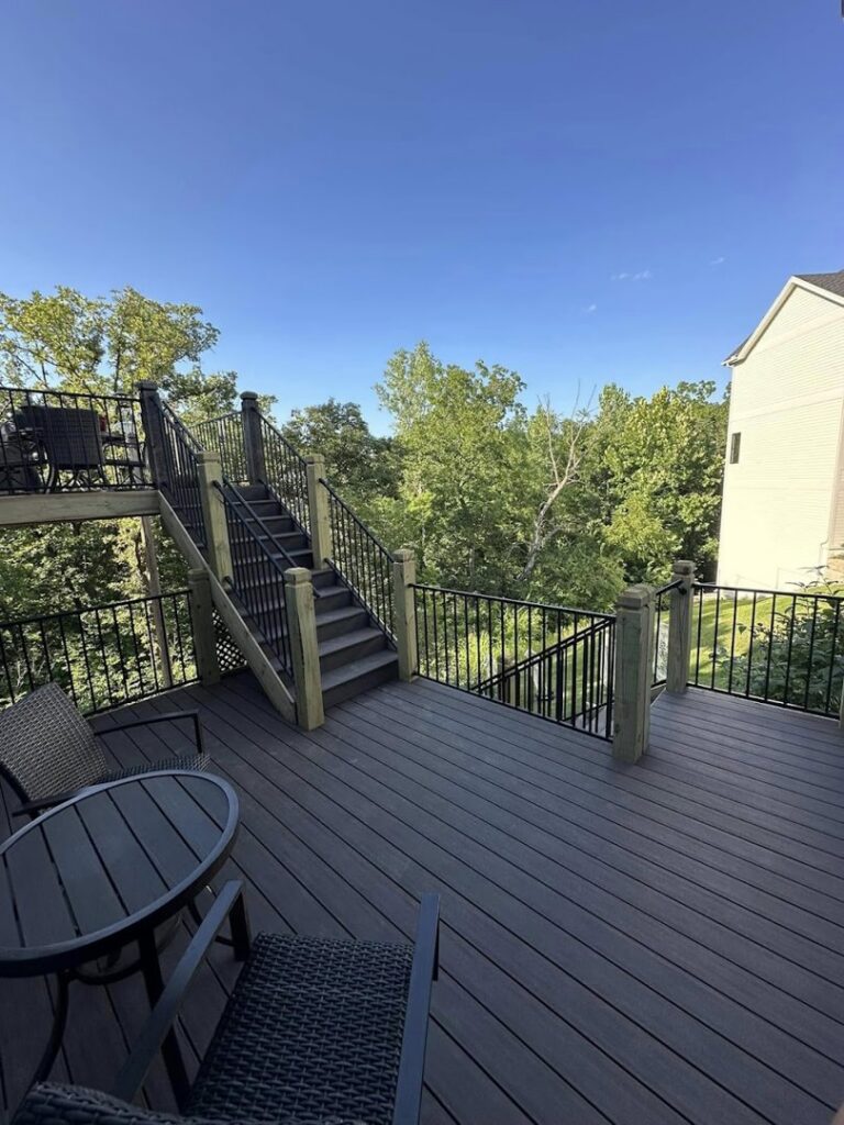 A spacious deck with stairs leading down to the yard, complete with outdoor seating by Deckscape KC in Kansas City, MO.