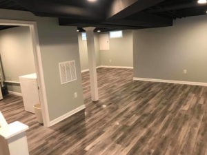 A spacious finished basement area with support columns and new flooring by M Zimmer Construction LLC in Rochester, NY.