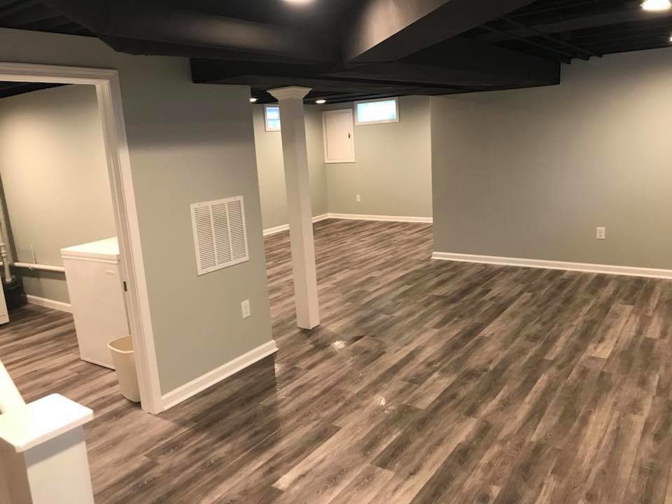 A spacious finished basement area with support columns and new flooring by M Zimmer Construction LLC in Rochester, NY.