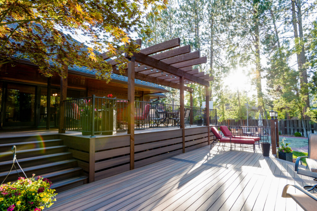 A spacious, finished composite deck featuring a wooden pergola and elegant railing, built by Ridgeline Decks in Spokane, WA.