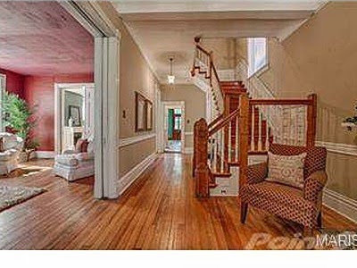 A spacious hallway leading to a wooden staircase and living room, demonstrating home remodeling expertise from Major League Handyman and Remodeling in St. Louis, MO.