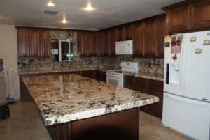 A spacious kitchen with dark granite countertops and wooden cabinets installed by L&M Granite Countertops in Phoenix, AZ.