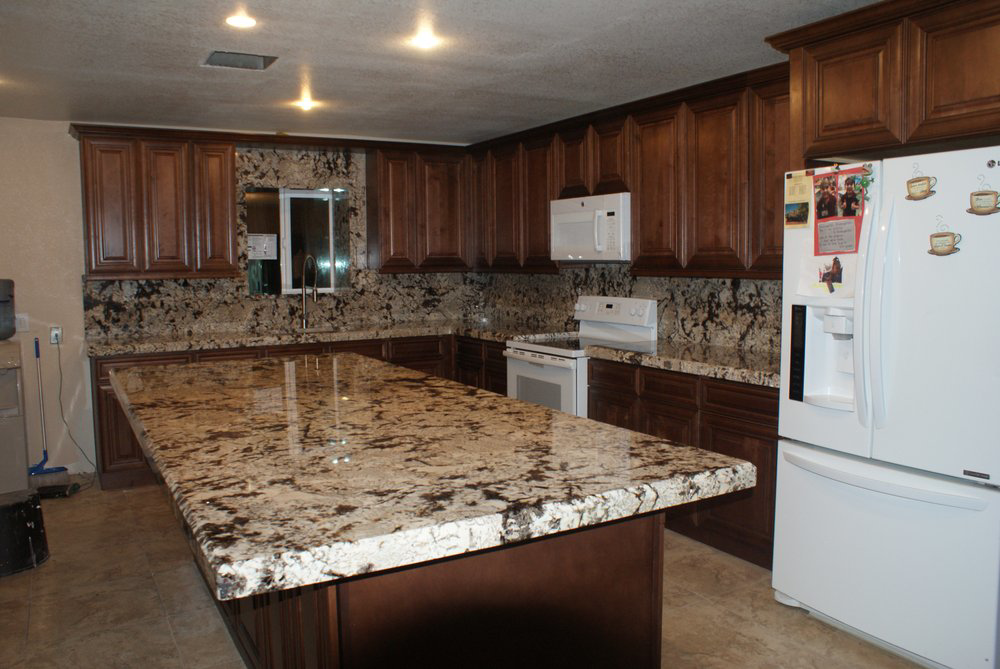 A spacious kitchen with dark granite countertops and wooden cabinets installed by L&M Granite Countertops in Phoenix, AZ.