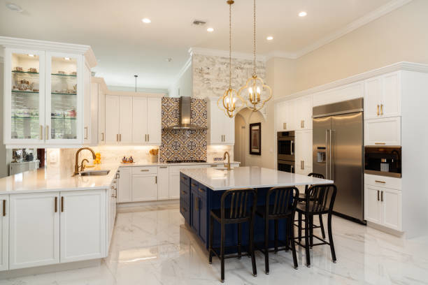 A spacious kitchen remodel with white cabinets, a blue island, and a stone accent wall by North Shore Kitchens in Pittsburgh, PA.