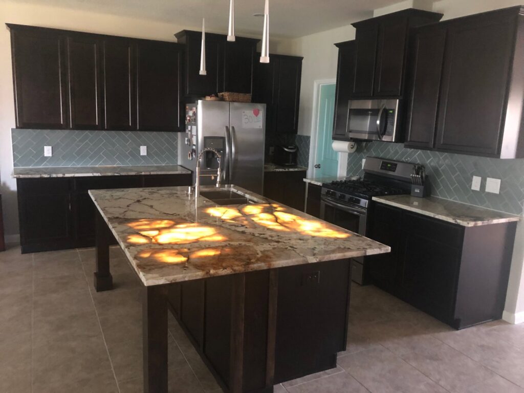 A spacious kitchen remodel featuring dark cabinets, a large island, and a tiled backsplash by MC Master Construction in League City, TX
