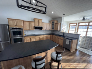 A spacious kitchen renovation with light wood cabinets, dark countertops, subway tile backsplash, and an island by JC Remodeling Ro LLC in Cleveland, OH.