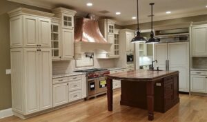 Spacious kitchen with white cabinets, large wooden island, and copper range hood by Charter Bay Home Builders in Tampa, FL
