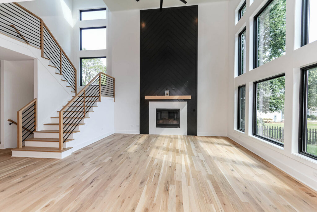 A spacious living room with high ceilings, a modern black fireplace, and a contemporary staircase by DJK Custom Homes in Naperville, IL