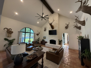 A spacious living room featuring a tall stone fireplace, high ceilings, and terracotta-style flooring, renovated by Javier's Painting in San Angelo, TX.