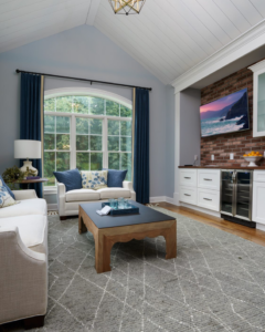 A spacious living room featuring a vaulted ceiling, large arched window, and built-in bar by Charlew Builders in Schenectady, NY.