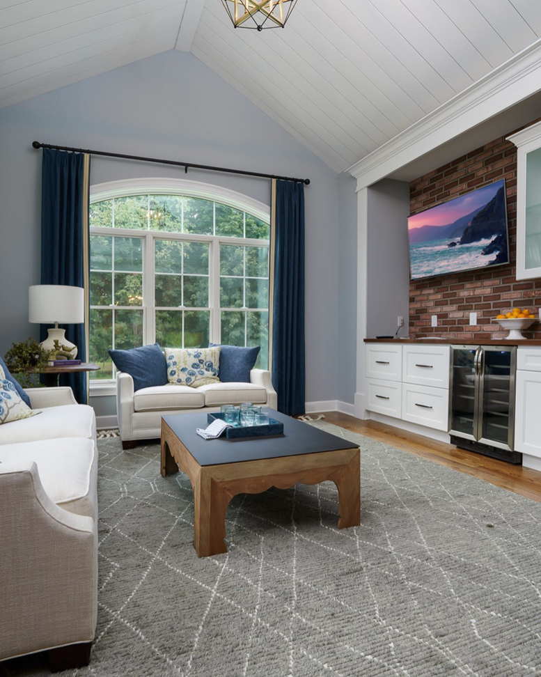 A spacious living room featuring a vaulted ceiling, large arched window, and built-in bar by Charlew Builders in Schenectady, NY.